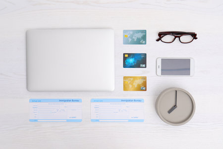 Flat lay composition with laptop, tickets and credit cards on wooden table in travel agency