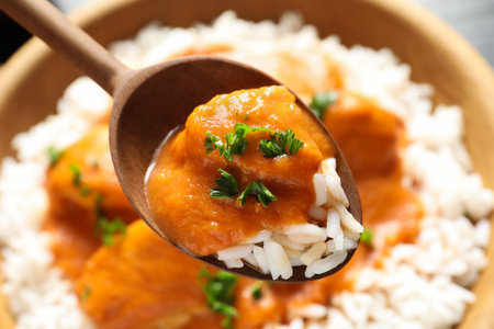 Spoon with tasty butter chicken over bowl of meal, closeupの写真素材