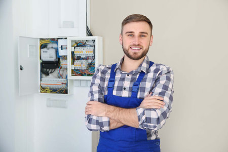 Male electrician standing near fuse board indoorsの写真素材