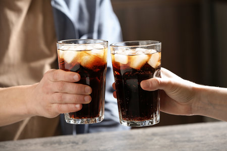 Couple with glasses of cold cola at table indoors, closeupの写真素材