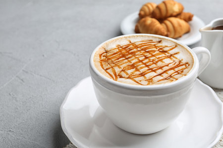 Cup of caramel macchiato and tasty pastry on tableの写真素材