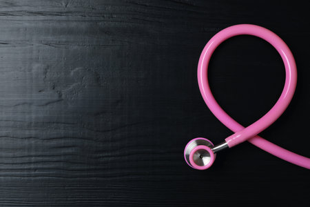 Pink stethoscope folded like awareness ribbon on wooden background, top view with space for text. breast cancer conceptの写真素材