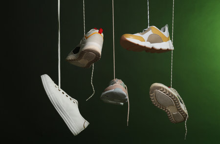 Different sneakers hanging on dark background. Stylish shoesの写真素材