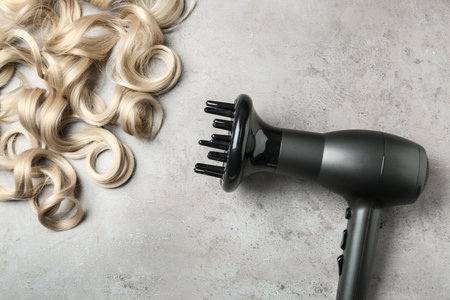 Curly hair locks and dryer on gray background, top viewの写真素材