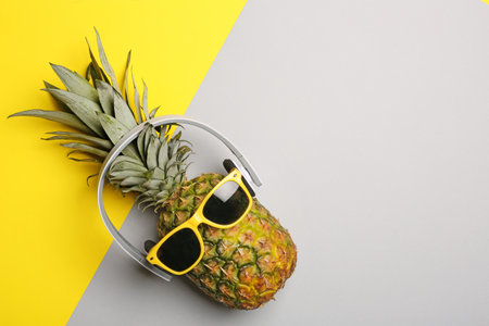 Funny pineapple with headphones and sunglasses on color background, top view. Space for textの写真素材