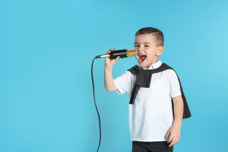 Cute funny boy with microphone on color background. Space for textの写真素材
