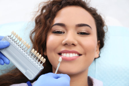 Dentist matching patient's teeth color with palette in officeの写真素材