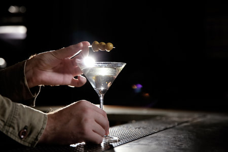 Barman adding olives to martini cocktail on counter, closeup. Space for textの写真素材