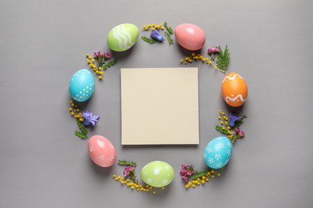 Flat lay composition of painted Easter eggs and blank card on color background, space for textの写真素材