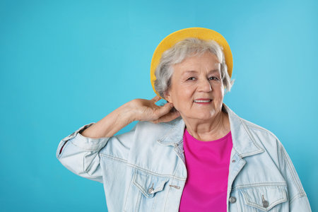 Portrait of mature woman in hipster outfit on color background