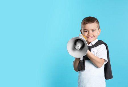 Cute funny boy with megaphone on color background. Space for textの写真素材
