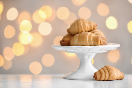 Cake stand with tasty pastry on table against blurred lights, space for textの写真素材
