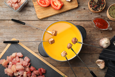 Flat lay composition with fondue pot and meat on wooden tableの写真素材