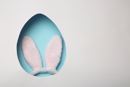 Top view of Easter bunny ears headband on color background through egg shaped hole, space for textの写真素材