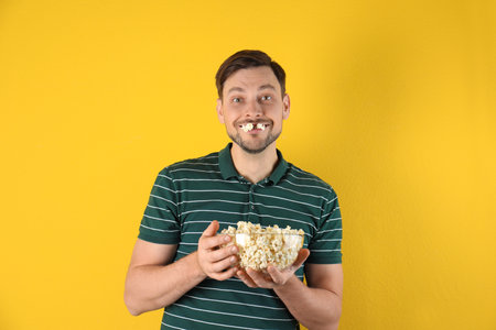 Man eating tasty popcorn on color backgroundの写真素材
