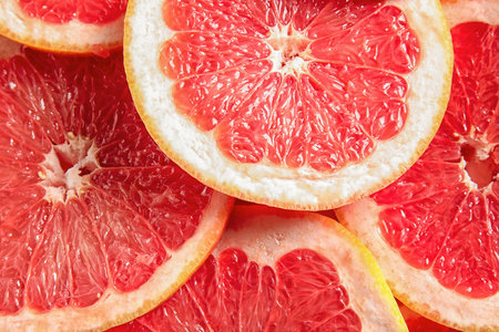 Many sliced fresh grapefruits as background, top viewの写真素材