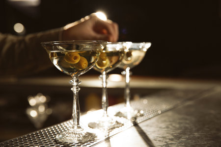 Barman adding olives to martini cocktail on counter, closeup. Space for textの写真素材