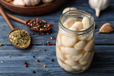 Preserved garlic in glass jar on wooden table. Space for textの写真素材