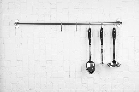 Rack with clean kitchen utensils on white white wall. Space for textの写真素材