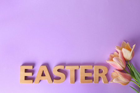 Spring flowers and word EASTER made of wooden letters on color background, top view. Space for textの写真素材