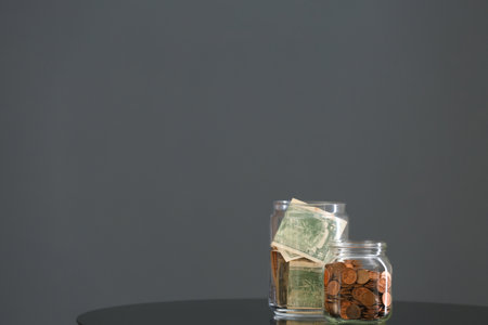 Donation jars with money on table against gray background. Space for textの写真素材