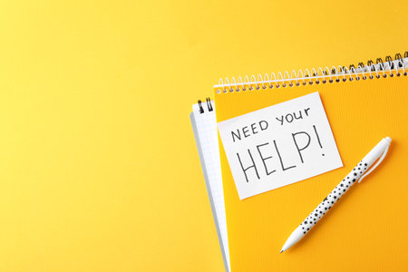 Flat lay composition with stationery and note NEED YOUR HELP on color background. Space for textの写真素材