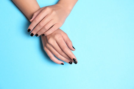 Woman showing black manicure on color background, space for text. Nail polish trendsの写真素材