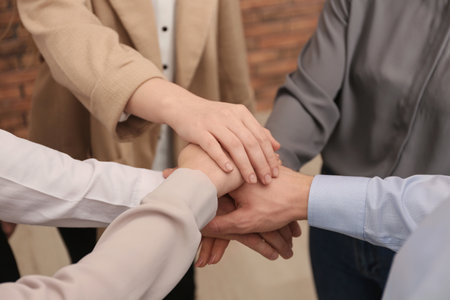 Group of people holding their hands together indoors, closeup