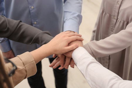 Group of people holding their hands together on blurred background, closeup