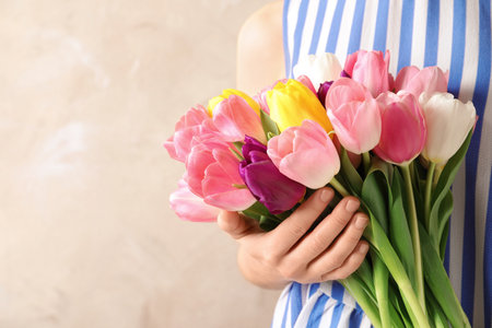 Girl holding bouquet of beautiful spring tulips on color background, closeup with space for text. International Women's Dayの写真素材