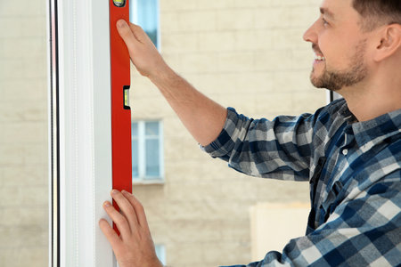Construction worker using bubble level while installing window indoors, closeupの写真素材