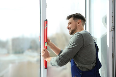 Construction worker using bubble level while installing window indoorsの写真素材