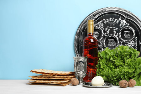 Symbolic Passover (Pesach) items on wooden table against color background, space for text