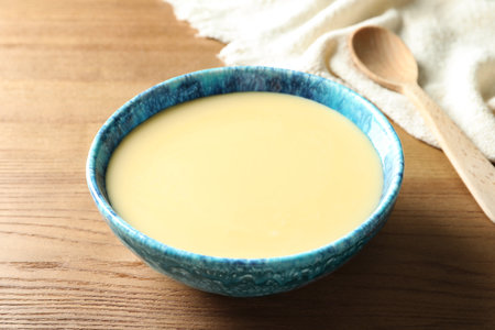 Bowl with condensed milk on wooden table. Dairy productsの写真素材