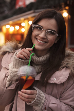 Woman with cup of mulled wine at winter fairの写真素材