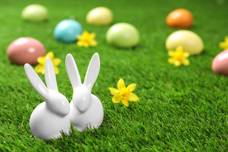 Ceramic Easter bunnies and dyed eggs on green grass, space for textの写真素材