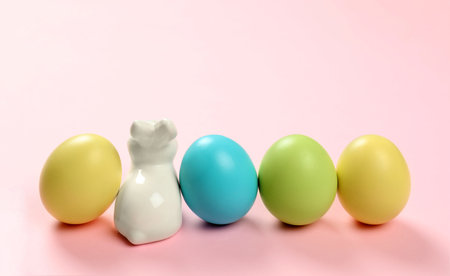 Ceramic Easter bunny and dyed eggs on color backgroundの写真素材