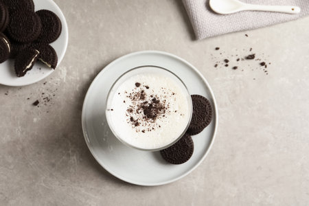 Glass of milk and chocolate cookies on gray background, top view