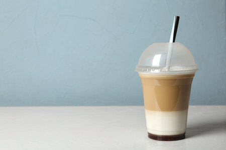 Plastic cup of tasty caramel macchiato on table, space for textの写真素材