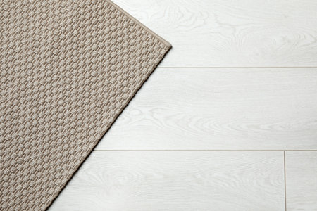 Woven mat on wooden background, top view with space for text