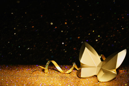 Golden glitter, decorative butterfly and streamer against black background. Space for textの写真素材