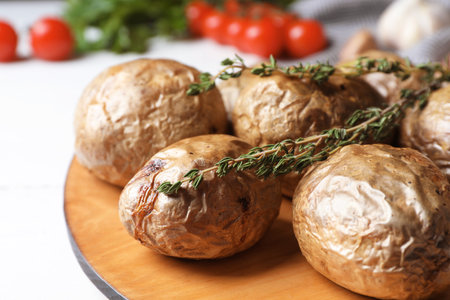 Board with tasty baked jacket potatoes on table, closeupの写真素材
