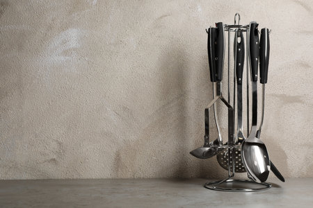 Holder with clean kitchen utensils on table. Space for textの写真素材