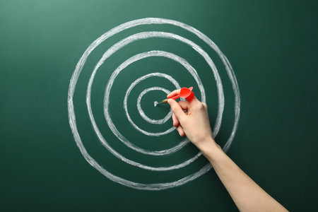 Woman with dart and chalk drawing of target on green background, closeup. Victory conceptの写真素材