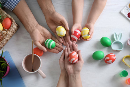 Father, mother and their child with painted Easter eggs on wooden background, top viewの写真素材