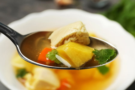 Spoon with fresh homemade chicken soup on blurred background, closeupの写真素材