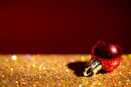 Golden paillettes and Christmas ball against color background. Space for textの写真素材