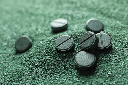 Natural green spirulina powder and pills as background, closeupの写真素材