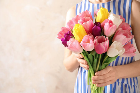 Girl holding bouquet of beautiful spring tulips on color background, closeup with space for text. International Women's Dayの写真素材