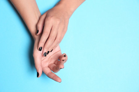 Woman showing black manicure on color background, top view with space for text. Nail polish trendsの写真素材
